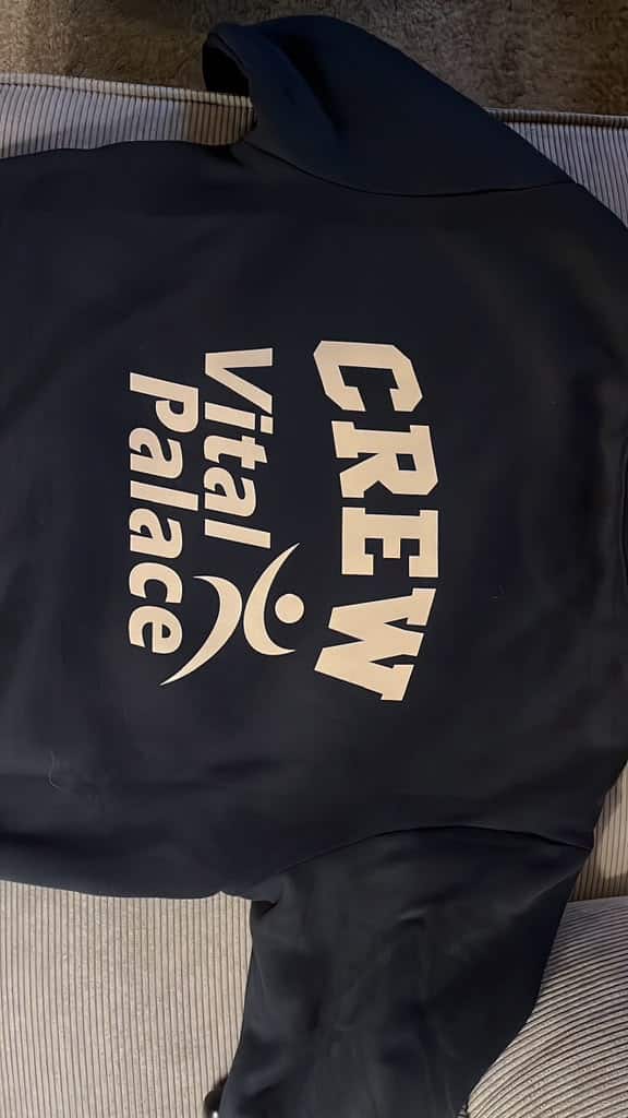 Donkere trui met CREW en het Vital Palace-logo op de rug.