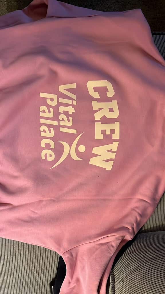 Roze trui met CREW en het Vital Palace-logo op de rug.